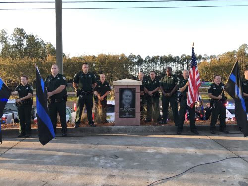 Officers hold flags next to Memorial to Deputy Eric Oliver